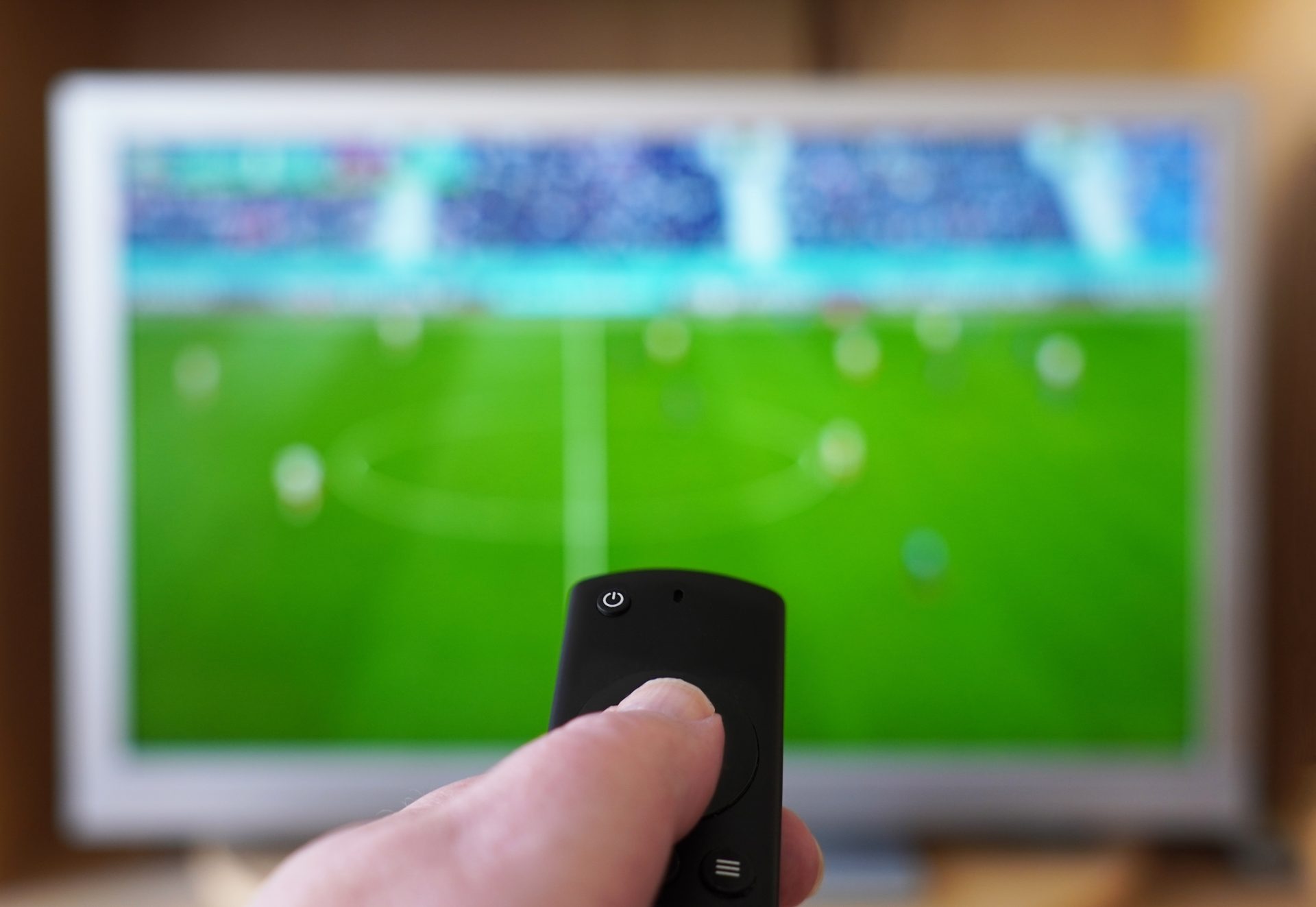 hand pointing remote control at tv with soccer mat 2023 11 27 05 30 16 utc